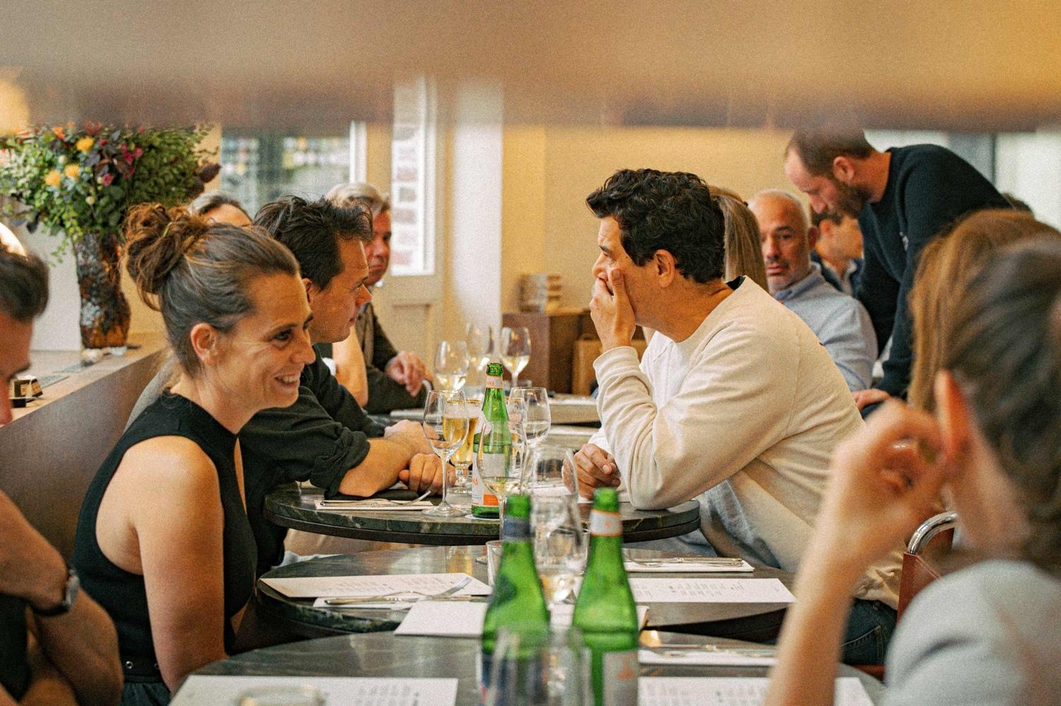 Mensen dineren aan de ronde tafeltjes van restaurant De Lieve
